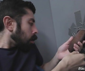 Bearded white man sucking and fucking a black cock at a gloryhole