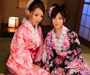 um par de japonês gueixa modelo juntos no seus brilhantemente colorido Kimonos