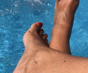 Mature woman Sweet Susi dips her painted toenails into a swimming pool