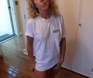 Older light-haired woman with curly hair hikes her T-shirt..