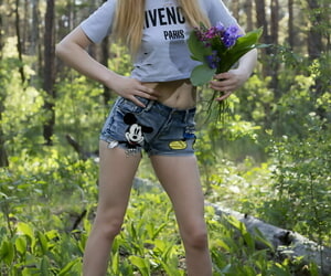 Nerdy blond Nika holds a bunch of wildflowers while..